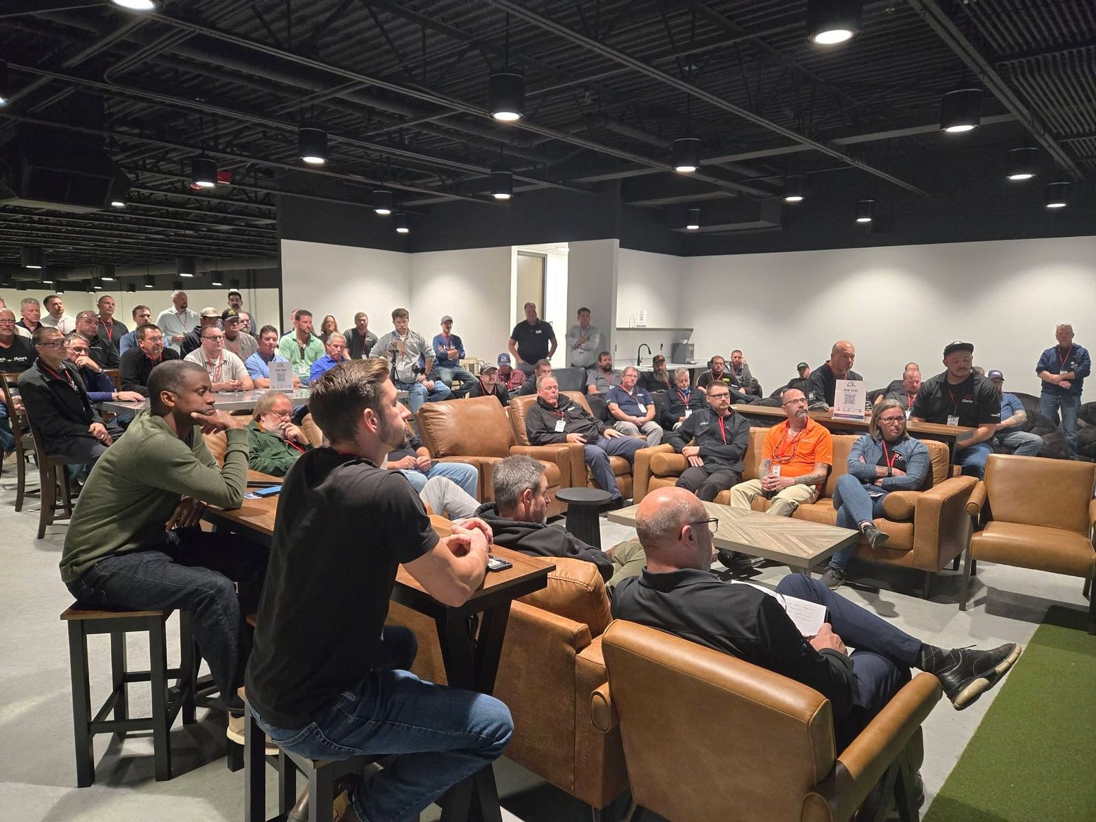 Attendees seated on couches and at high-top tables listening to the program